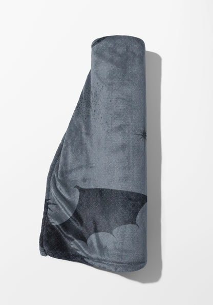 Gray blanket with bat graphic and starburst pattern, rolled on white background.