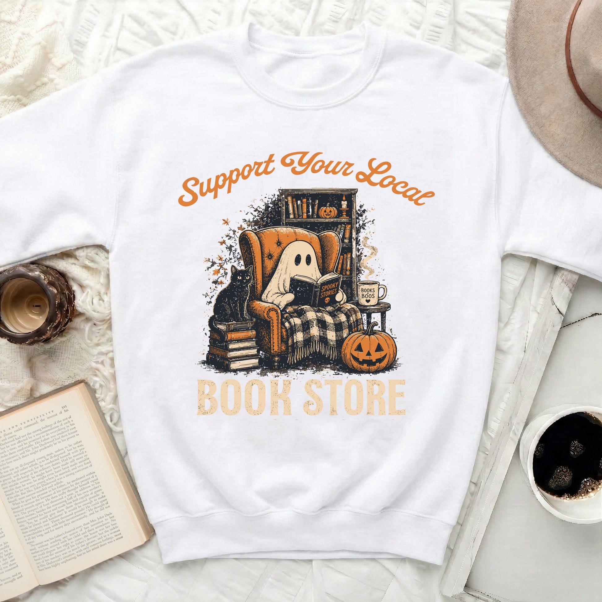 White graphic sweatshirt with "Support Your Local Book Store" and a ghost reading.