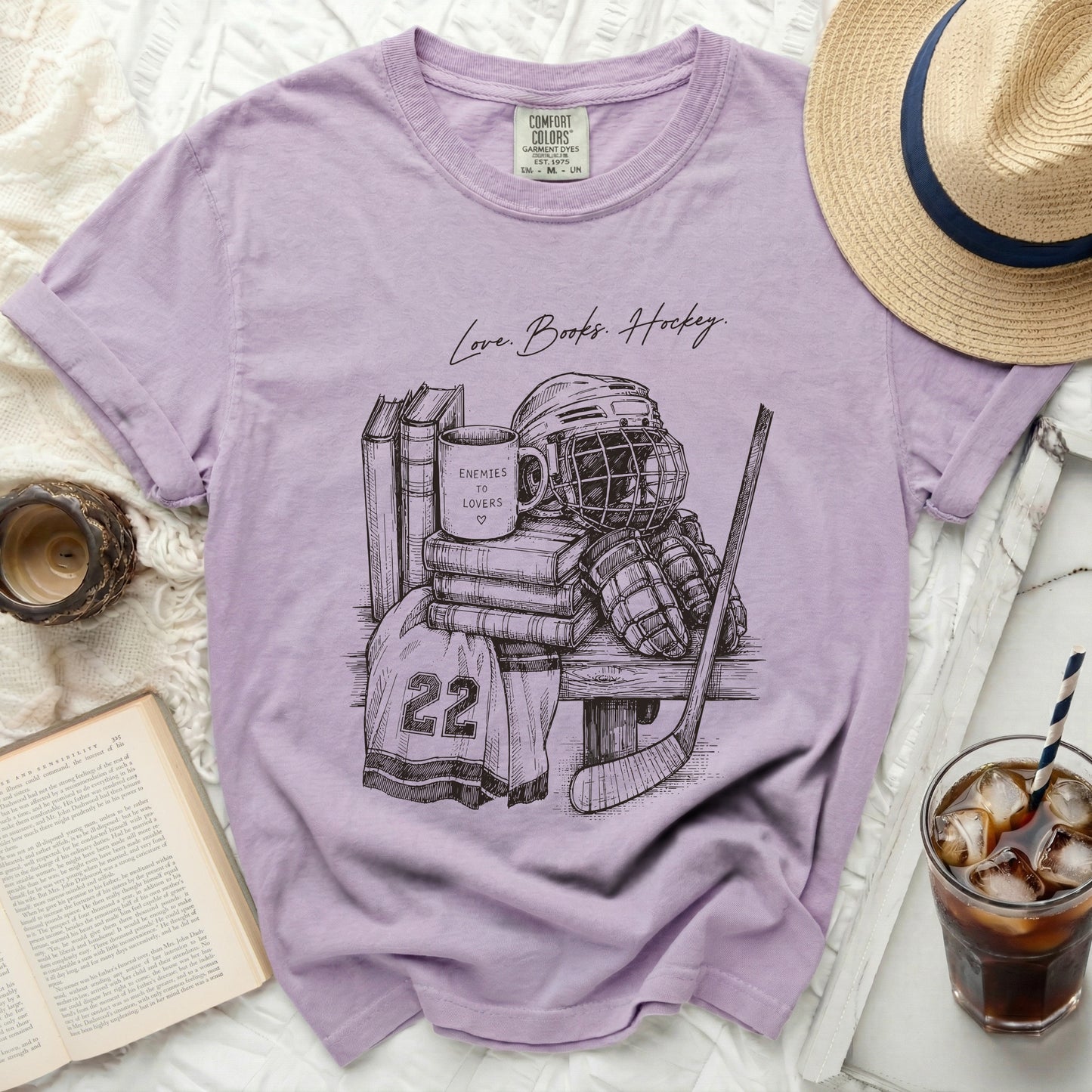 T-shirt with sketch of hockey gear, books, and mug with "Enemies to Lovers" text.
