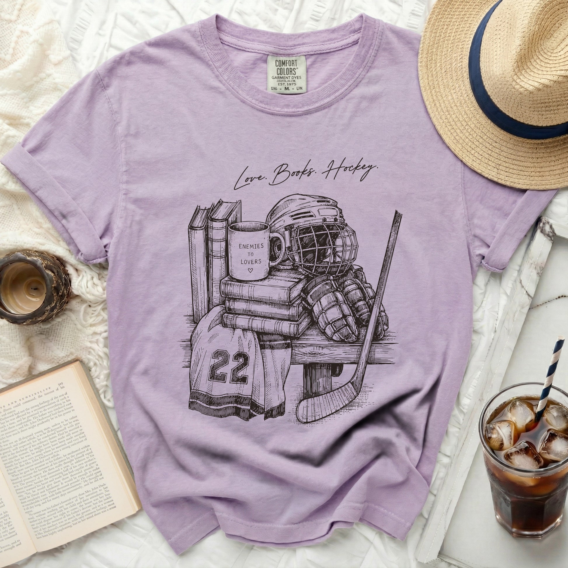 T-shirt with sketch of hockey gear, books, and mug with "Enemies to Lovers" text.