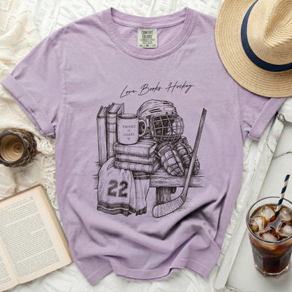 T-shirt with sketch of hockey gear, books, and mug with "Enemies to Lovers" text.
