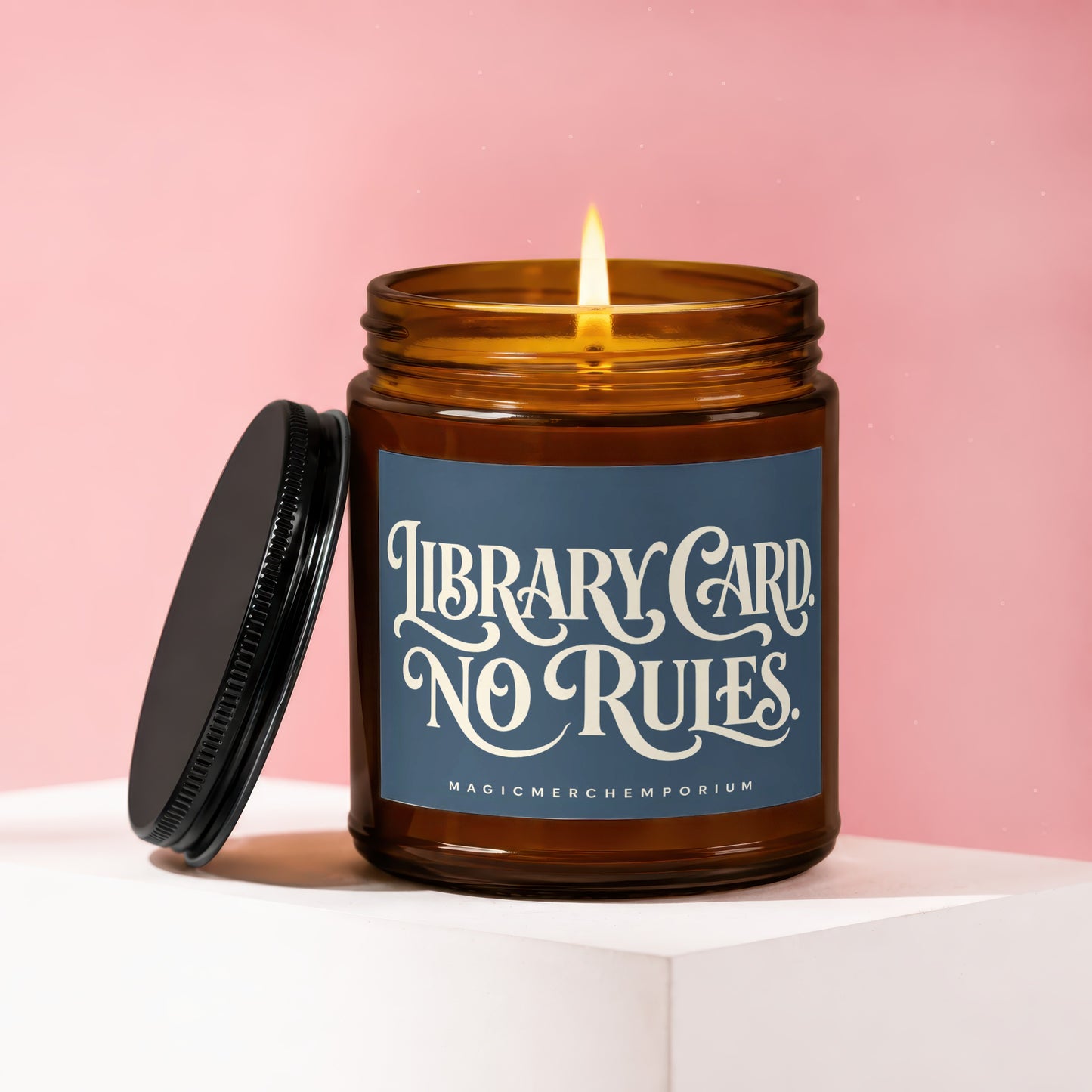 Amber candle with lit flame and dark lid, reading "Library Card No Rules".