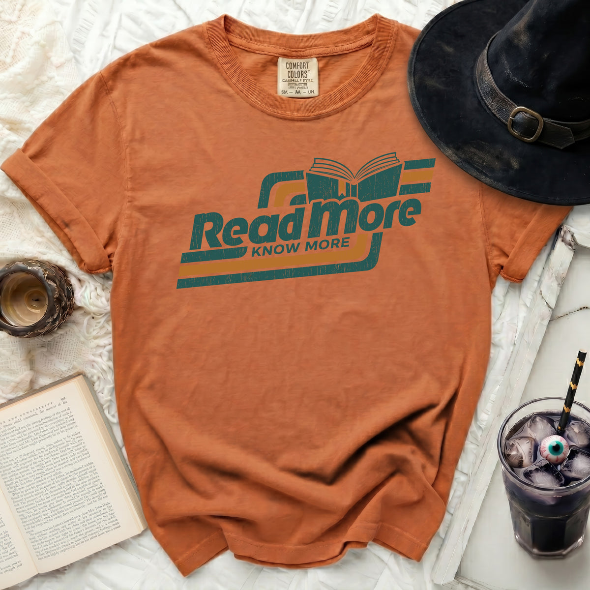 Orange t-shirt with "Read More Know More" graphic and open book design.
