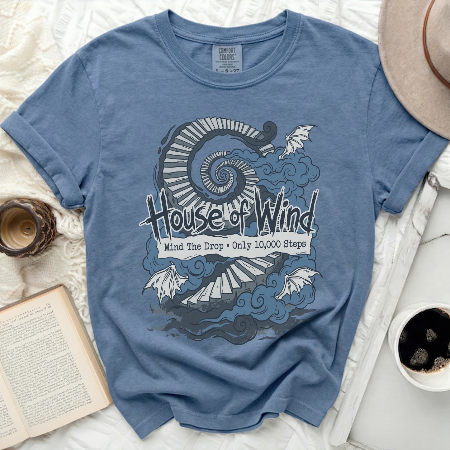 Blue t-shirt with "House of Wind Mind The Drop Only 10,000 Steps" graphic.
