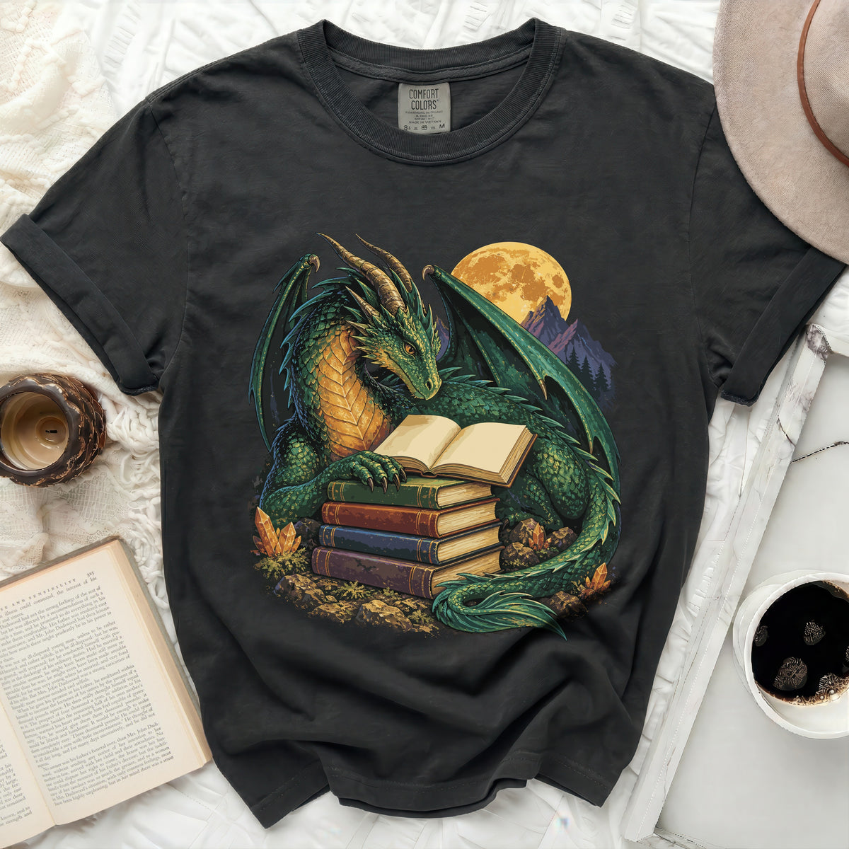 Dark t-shirt with a green dragon reading books under a full moon.