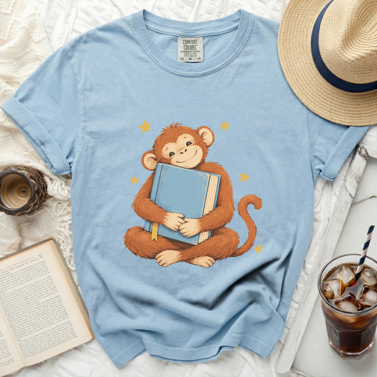 Blue t-shirt with a monkey hugging a book and yellow stars graphic.