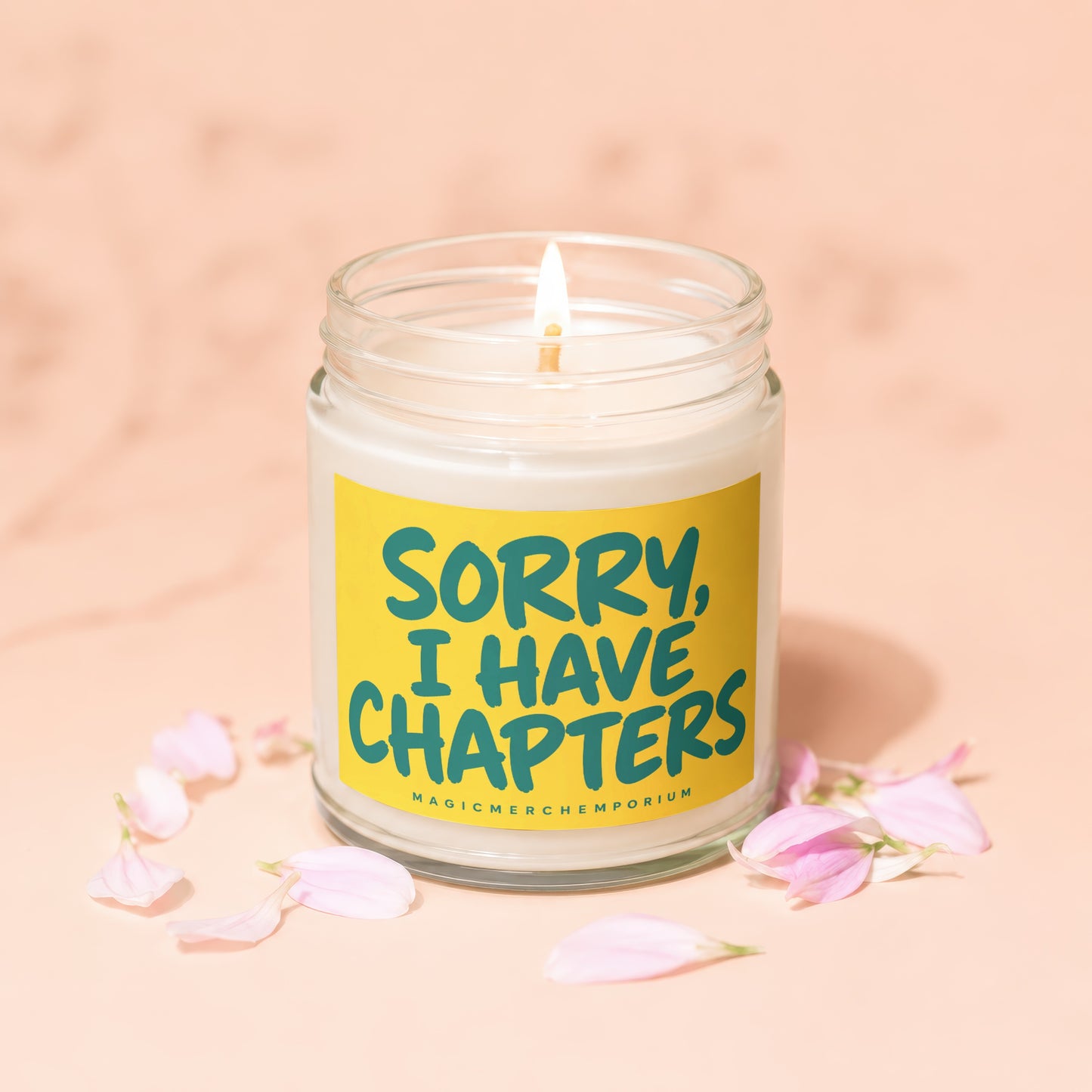 Candle with yellow label reading "SORRY, I HAVE CHAPTERS" surrounded by pink petals.