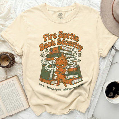 Yellow t-shirt with a cartoon fire sprite guarding a stack of books.