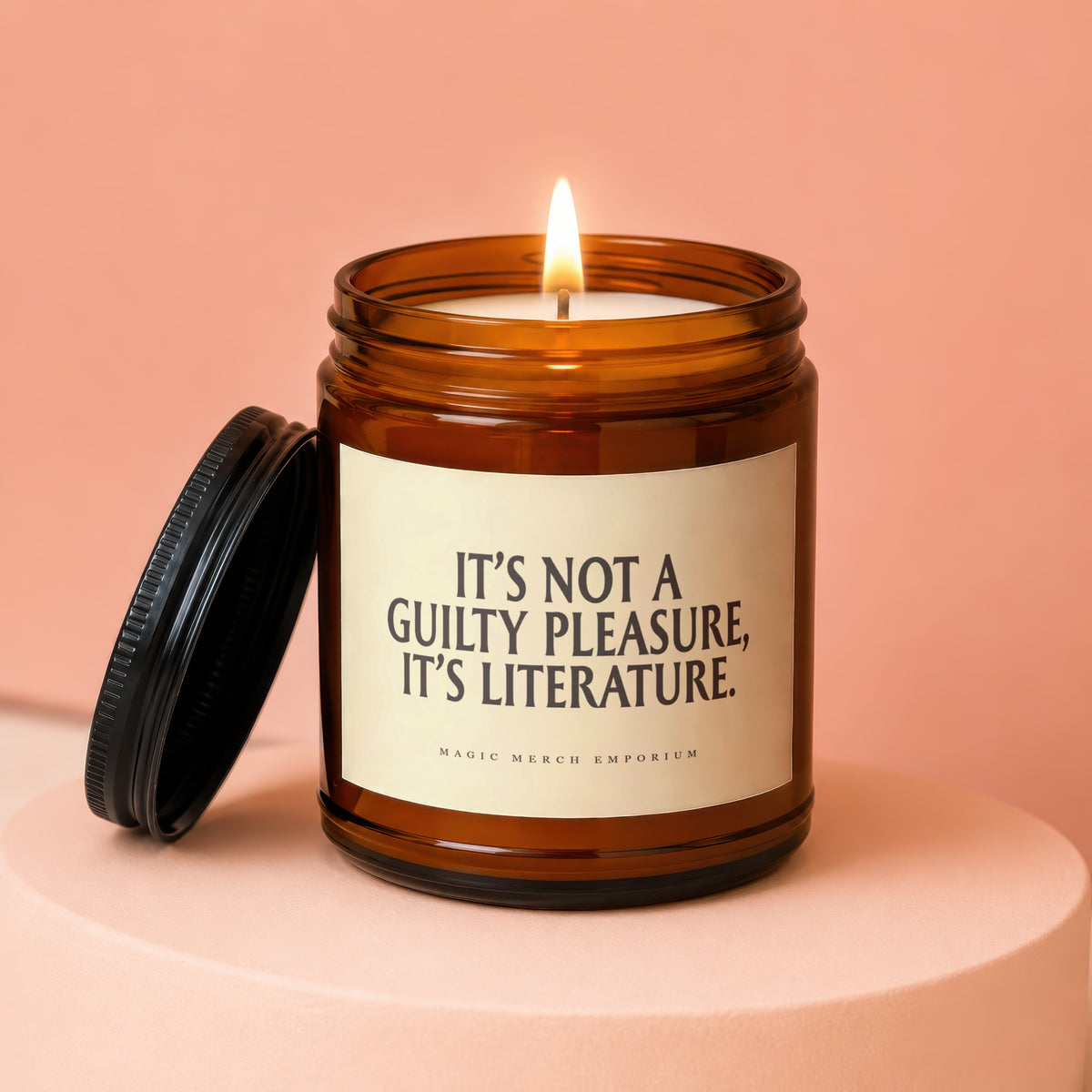 Amber jar candle with lit flame, featuring text "IT'S NOT A GUILTY PLEASURE, IT'S LITERATURE."