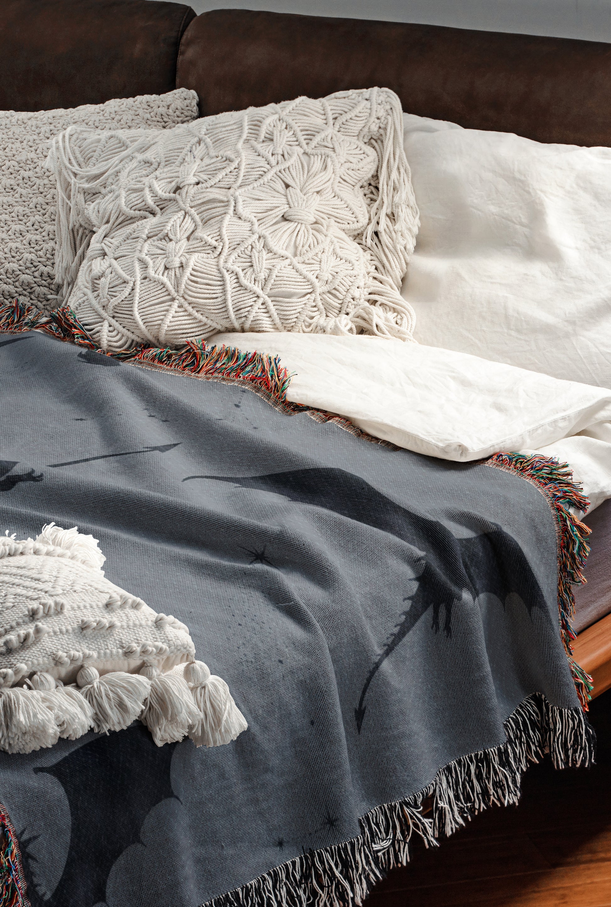 a cozy and inviting bedroom scene, featuring a comfortable bed with a gray blanket and white pillows, as well as a brown leather couch.