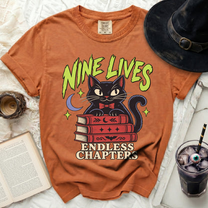Orange t-shirt with black cat on books, "Nine Lives Endless Chapters" text