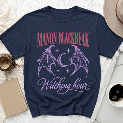 Navy t-shirt with "MANON BLACKBEAK" and "Witching hour" text with gothic wings and moon graphic.