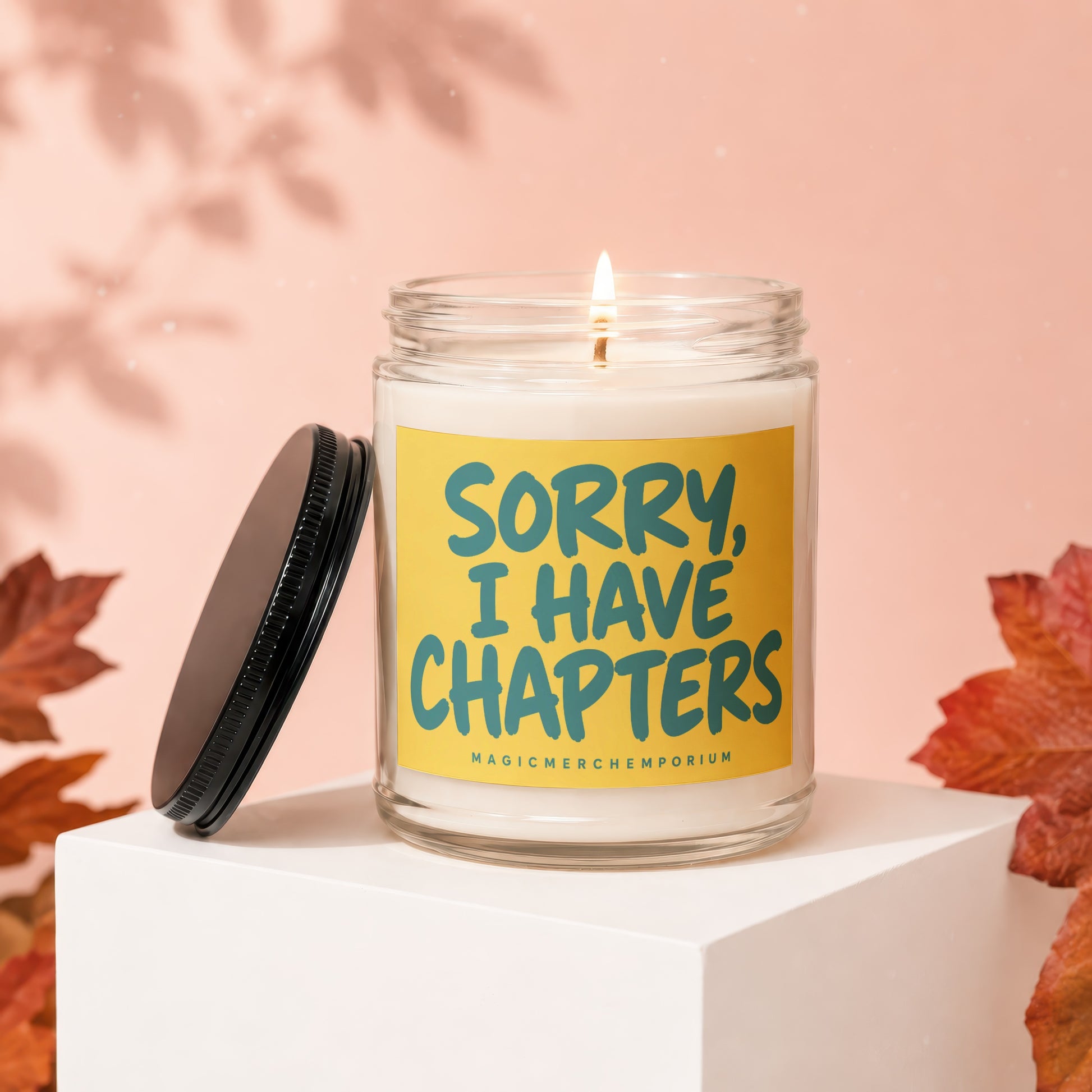 Lit candle in jar with yellow label saying "Sorry, I Have Chapters" and "MagicMerchEmporium".