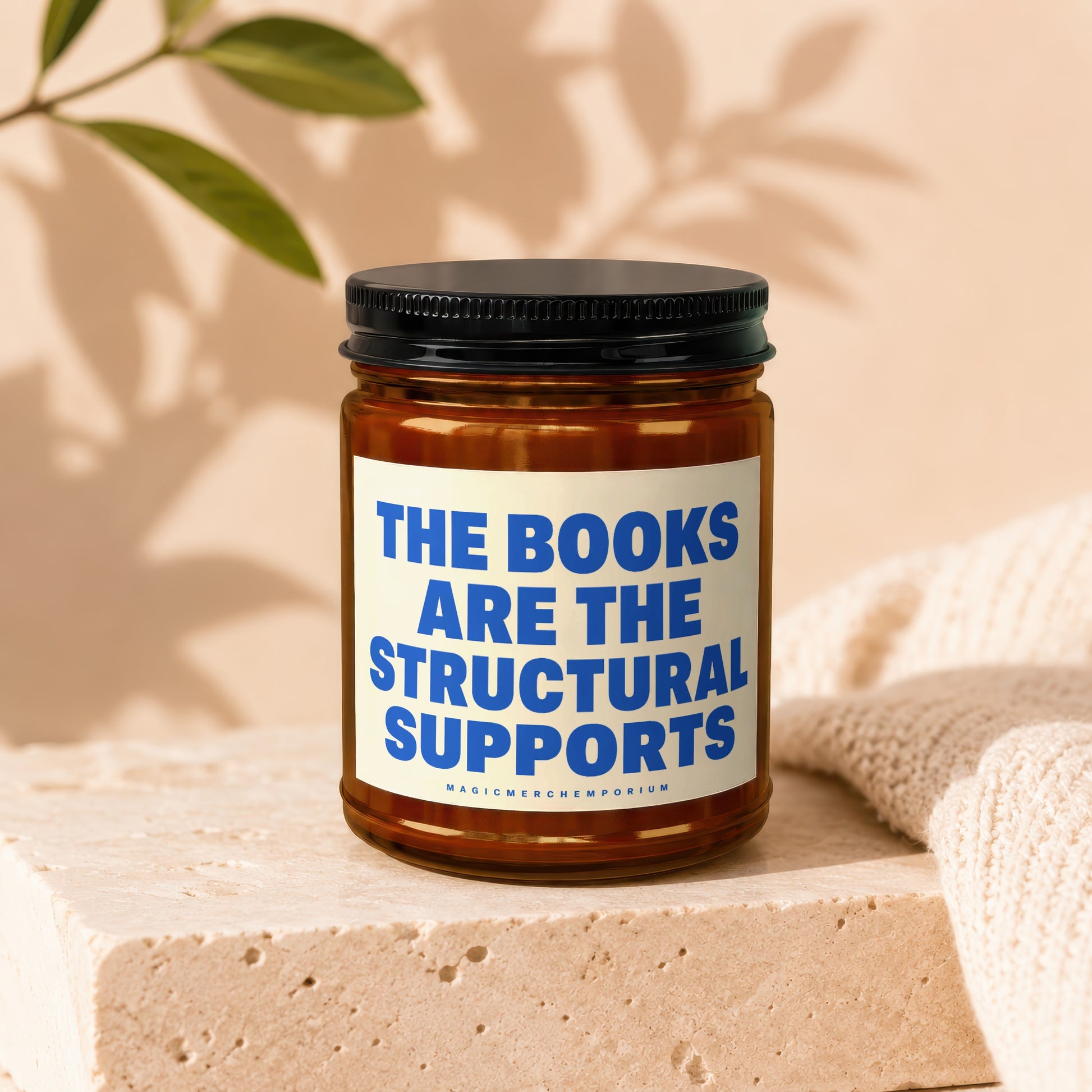Amber jar candle with label "The Books Are The Structural Supports"