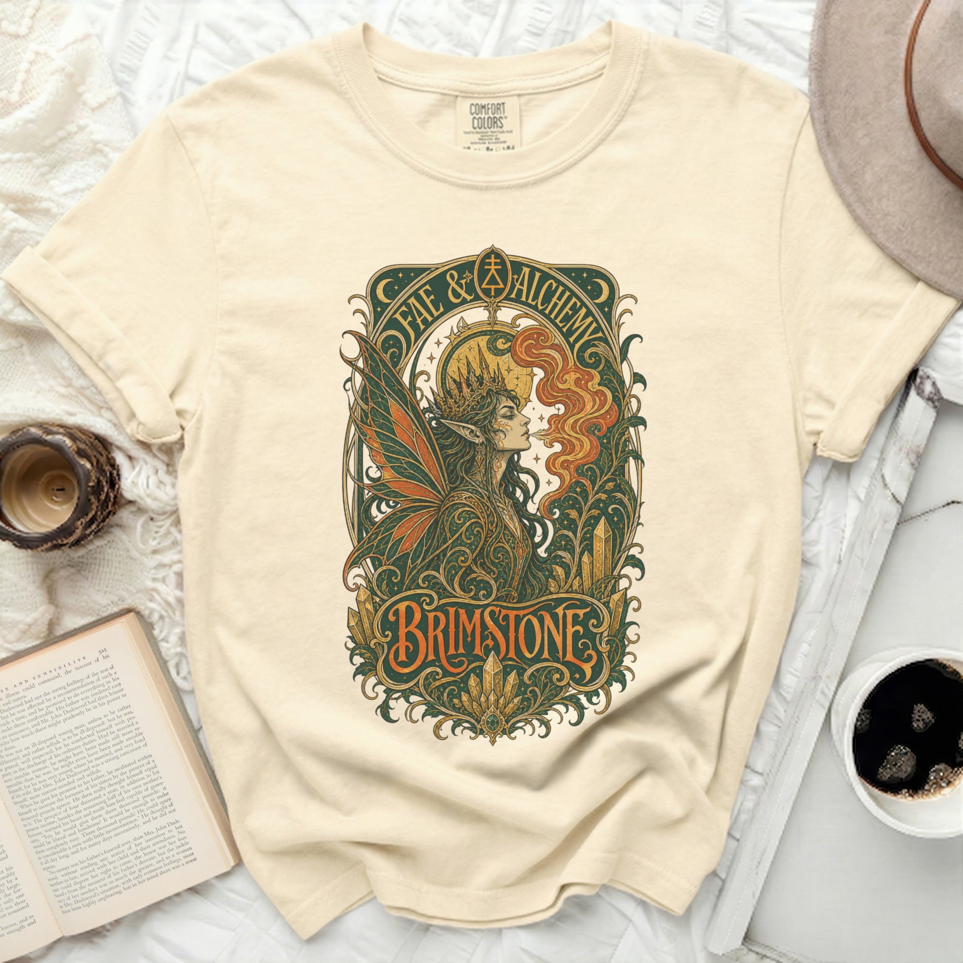 Cream t-shirt with "Fae & Alchemy Brimstone" graphic featuring a winged figure.