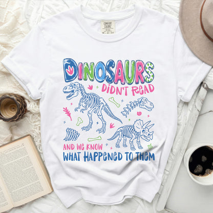 White t-shirt with "Dinosaurs Didn't Read And We Know What Happened To Them" graphic.