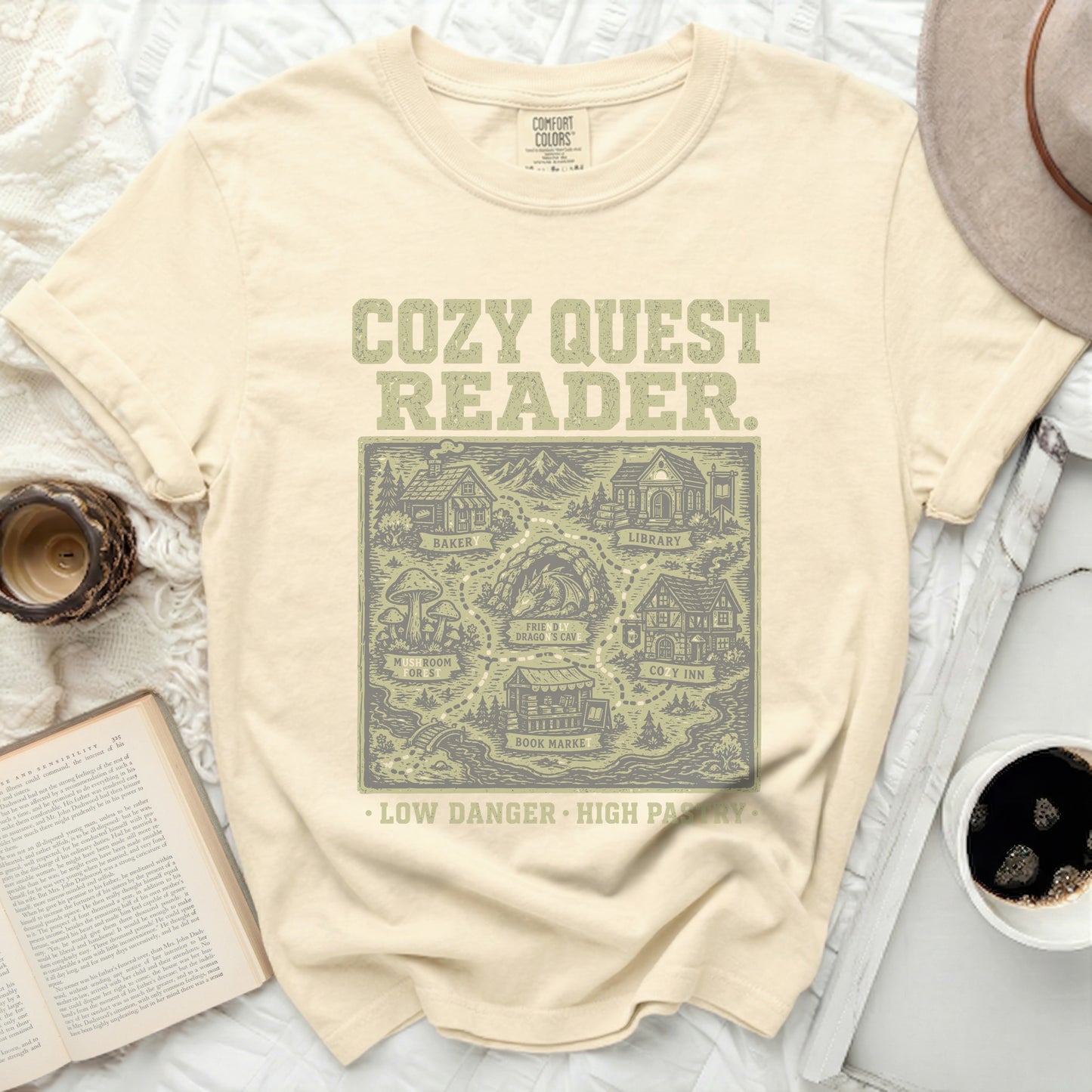 Cream t-shirt with "Cozy Quest Reader" and fantasy map graphic.