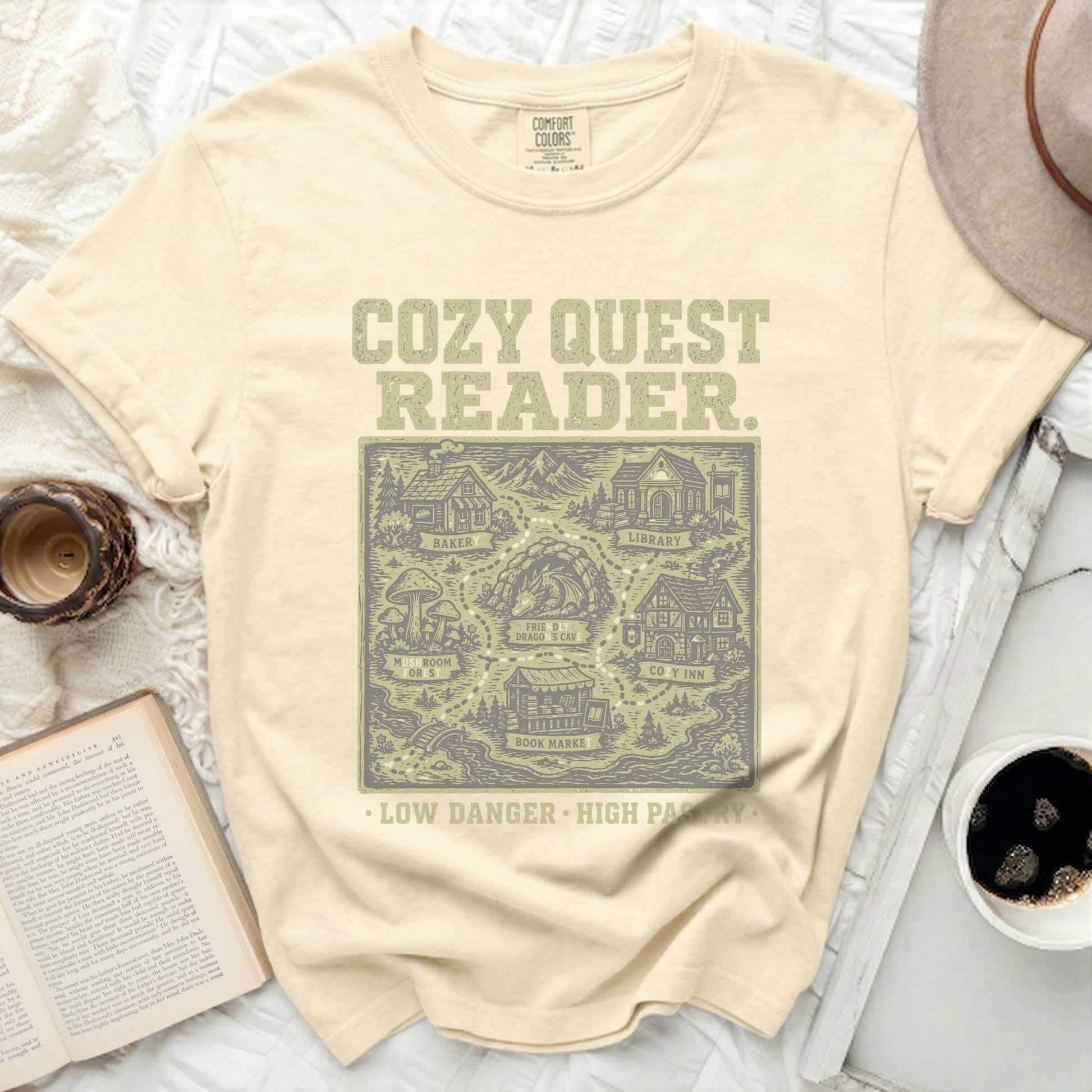 Cream t-shirt with "Cozy Quest Reader" and fantasy map graphic.