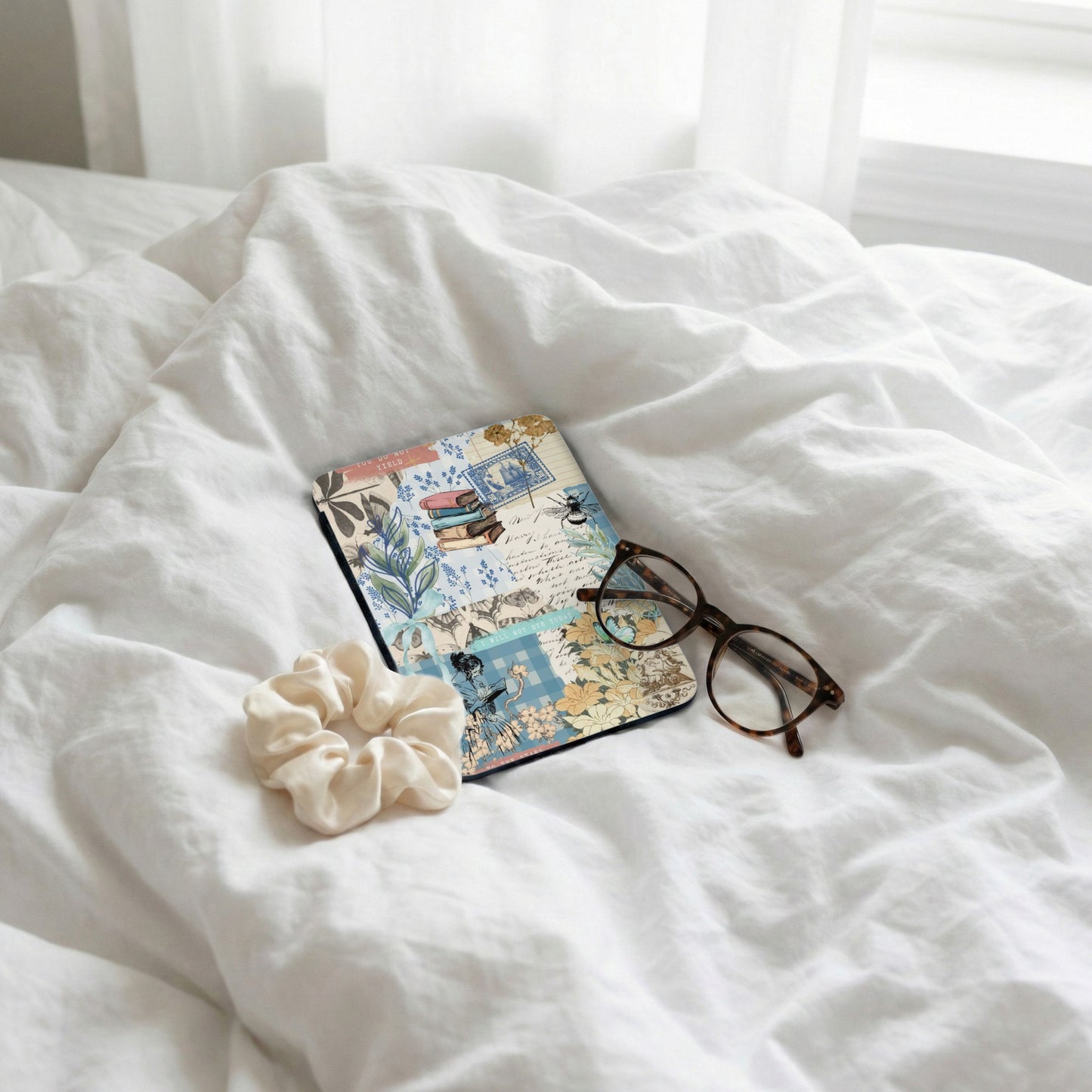 Collage journal with books, bee, and text, next to glasses and scrunchie.