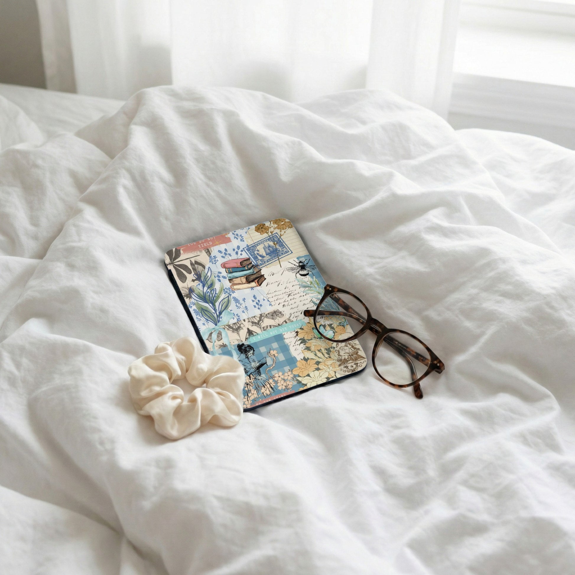 Collage journal with books, bee, and text, next to glasses and scrunchie.