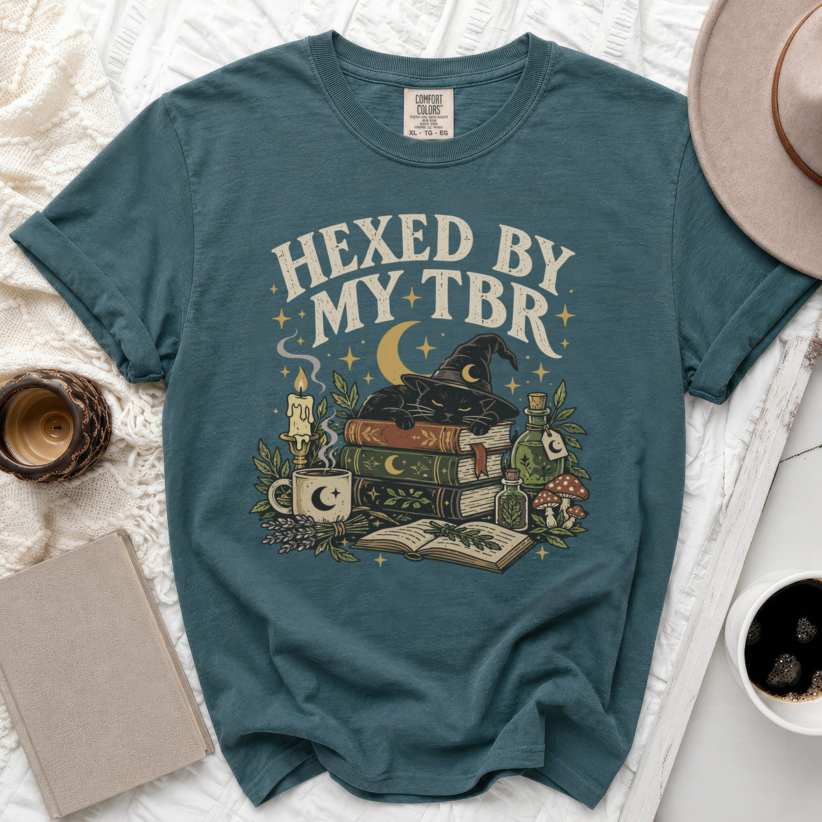 Teal t-shirt with graphic of black cat, books, and text "HEXED BY MY TBR".