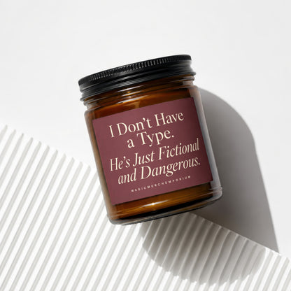 Brown glass candle with black lid and label reading "I Don't Have a Type. He's Just Fictional and Dangerous."