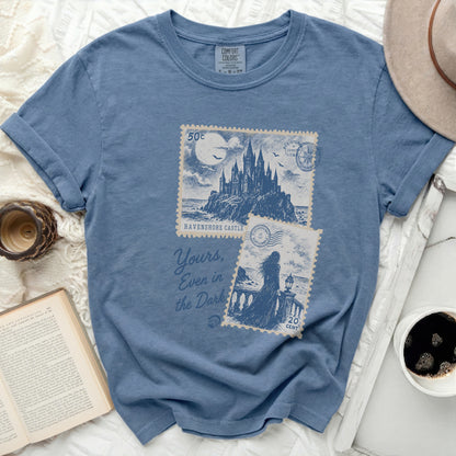 Blue t-shirt with "Ravenshore Castle" graphic and handwritten text.