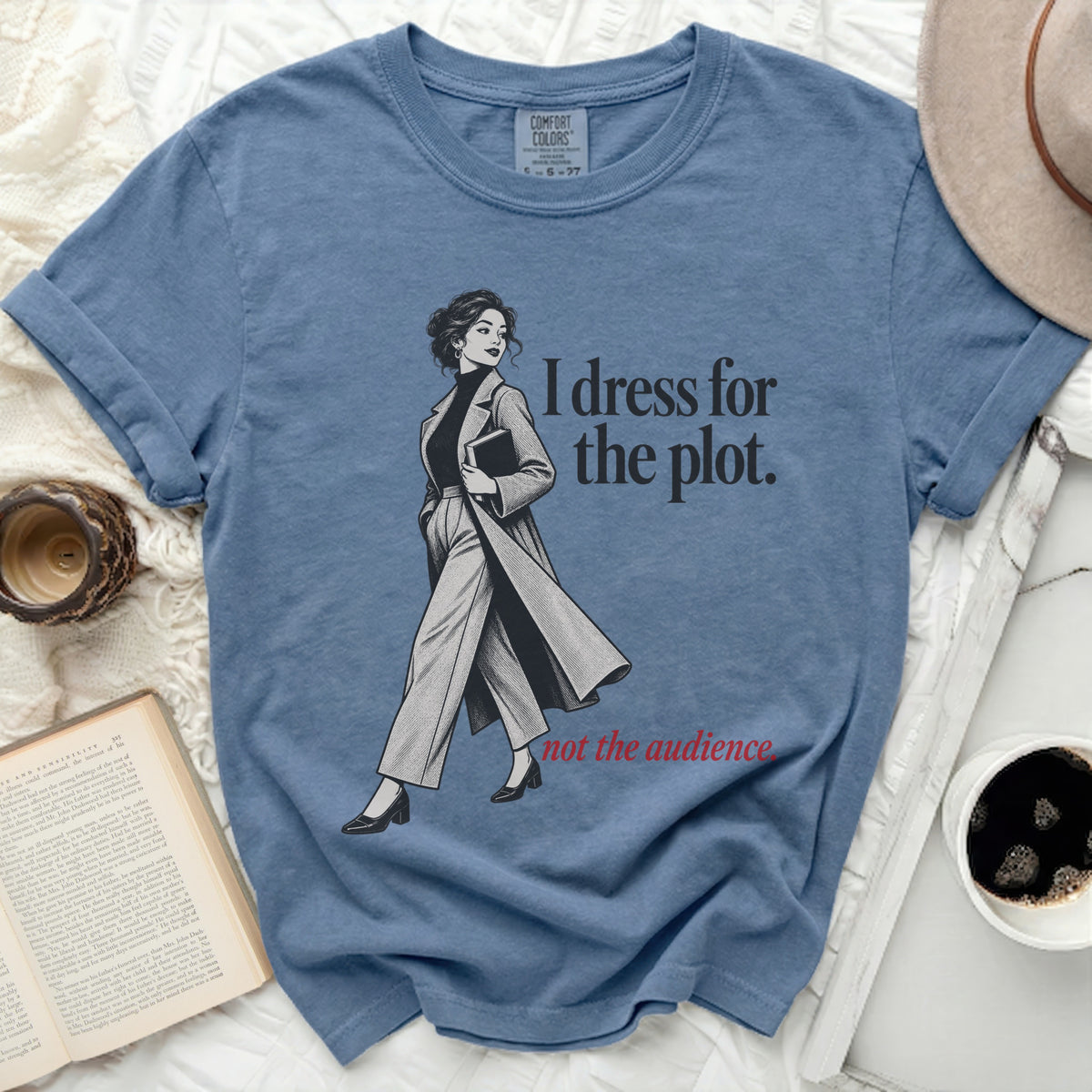 Blue t-shirt with illustration of woman and text "I dress for the plot. not the audience."