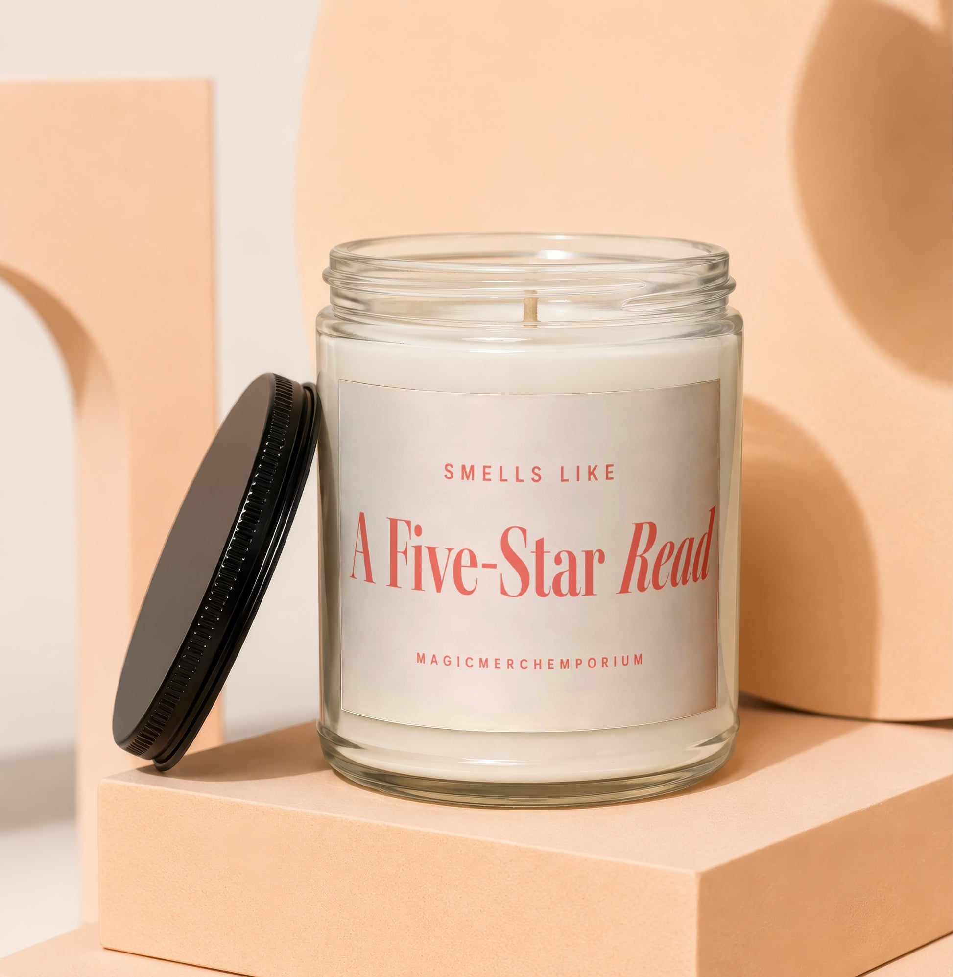 Candle with label reading "Smells Like A Five-Star Read" on peach pedestals.