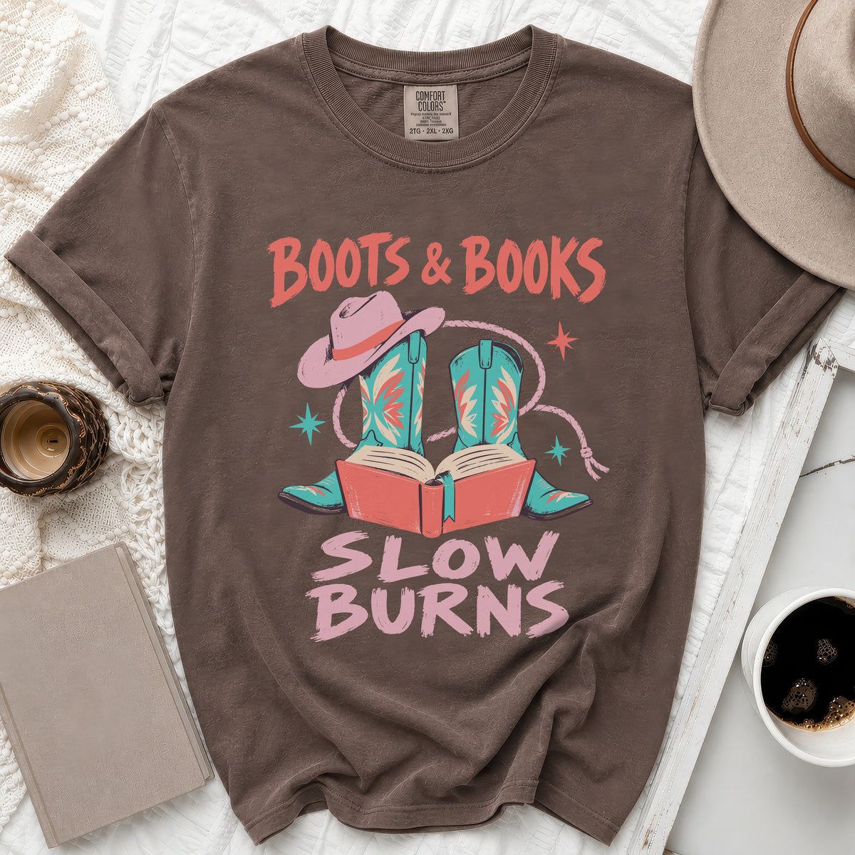 Brown t-shirt with "Boots & Books Slow Burns" graphic featuring cowboy boots, hat, and open book.