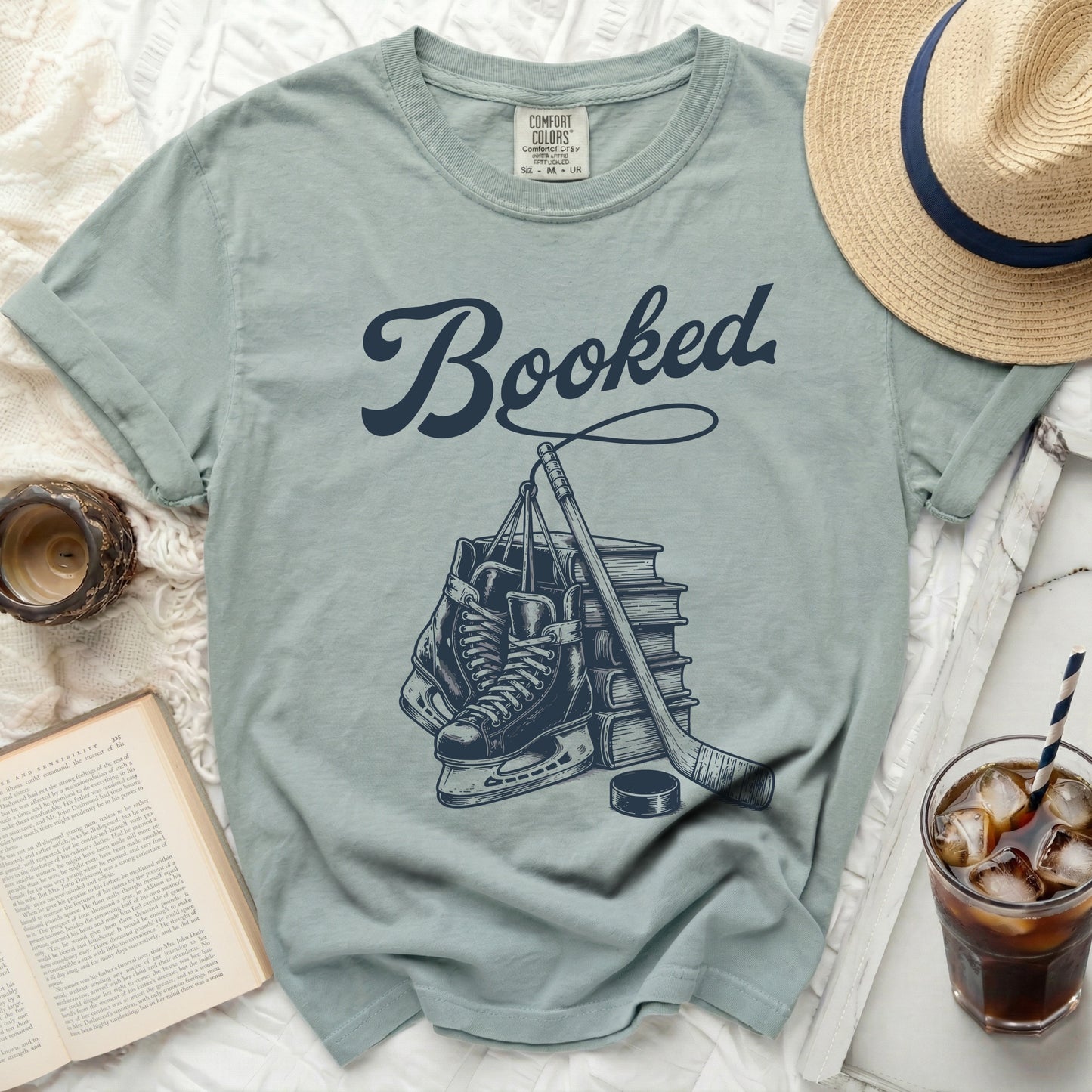 T-shirt with "Booked" text and illustration of hockey gear and books.