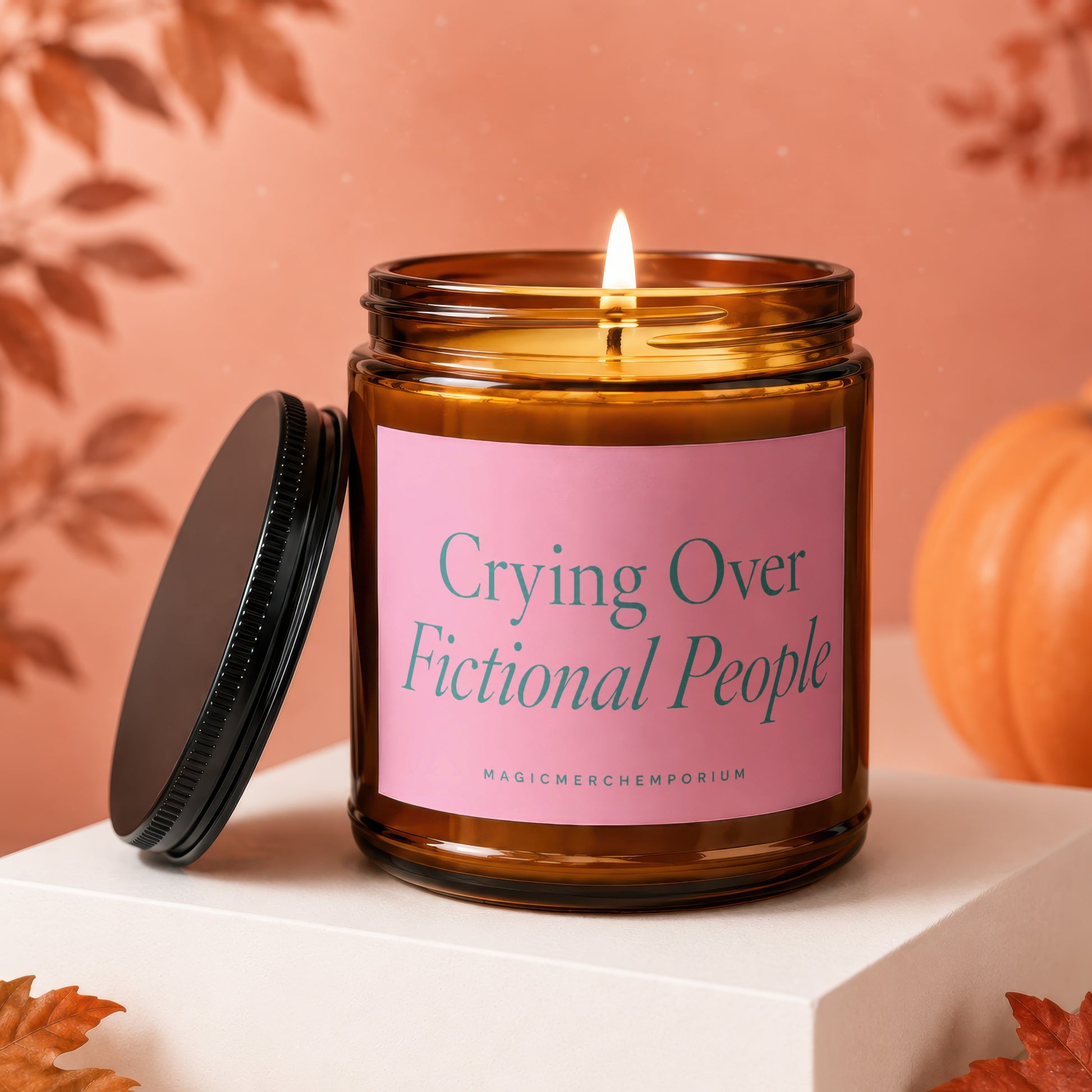 Lit candle in amber jar with pink label that reads "Crying Over Fictional People".