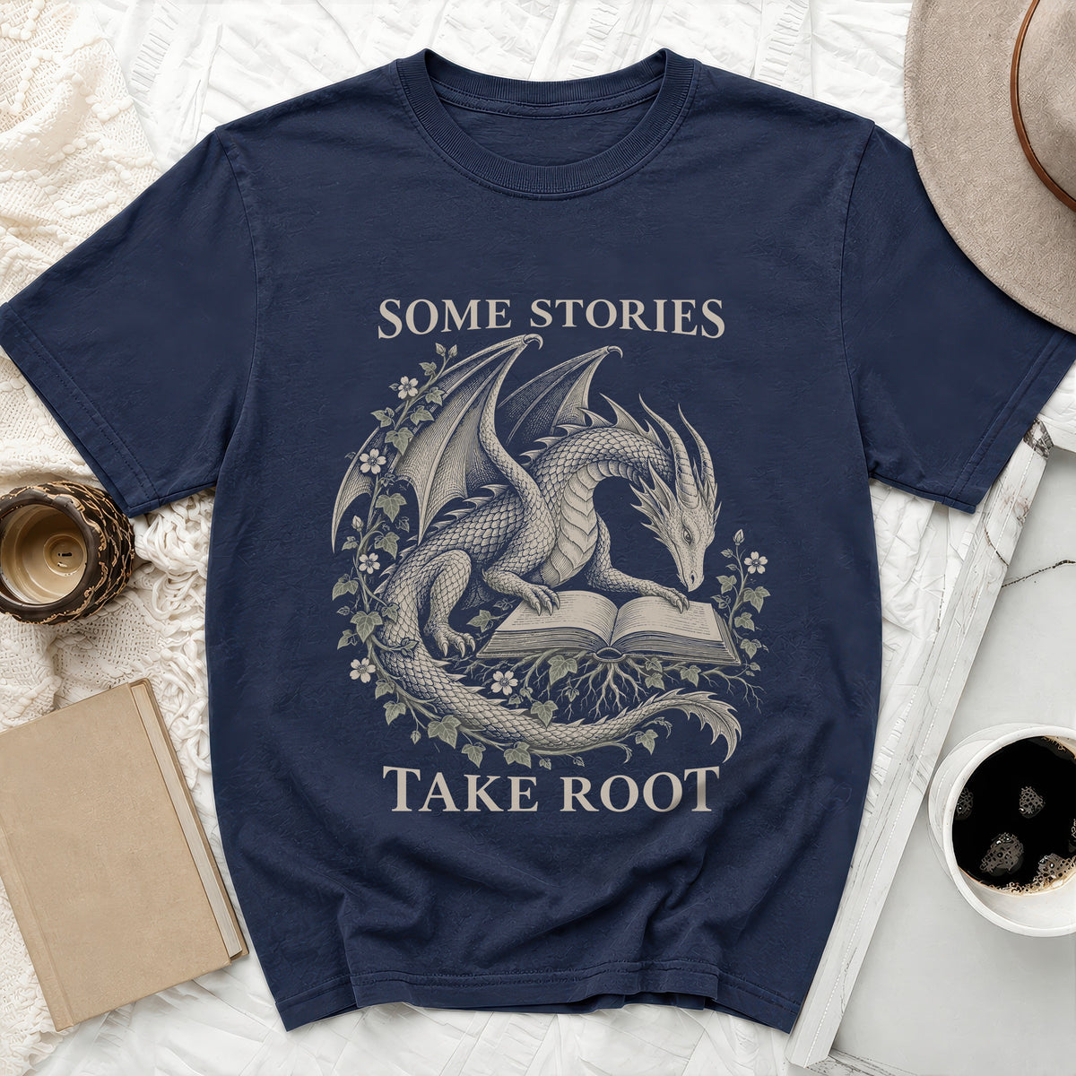 Navy t-shirt with dragon reading book graphic and text "Some Stories Take Root".