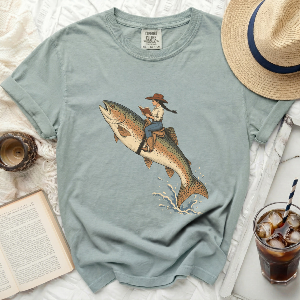 Girl in cowboy hat riding a flying rainbow trout and reading a book.