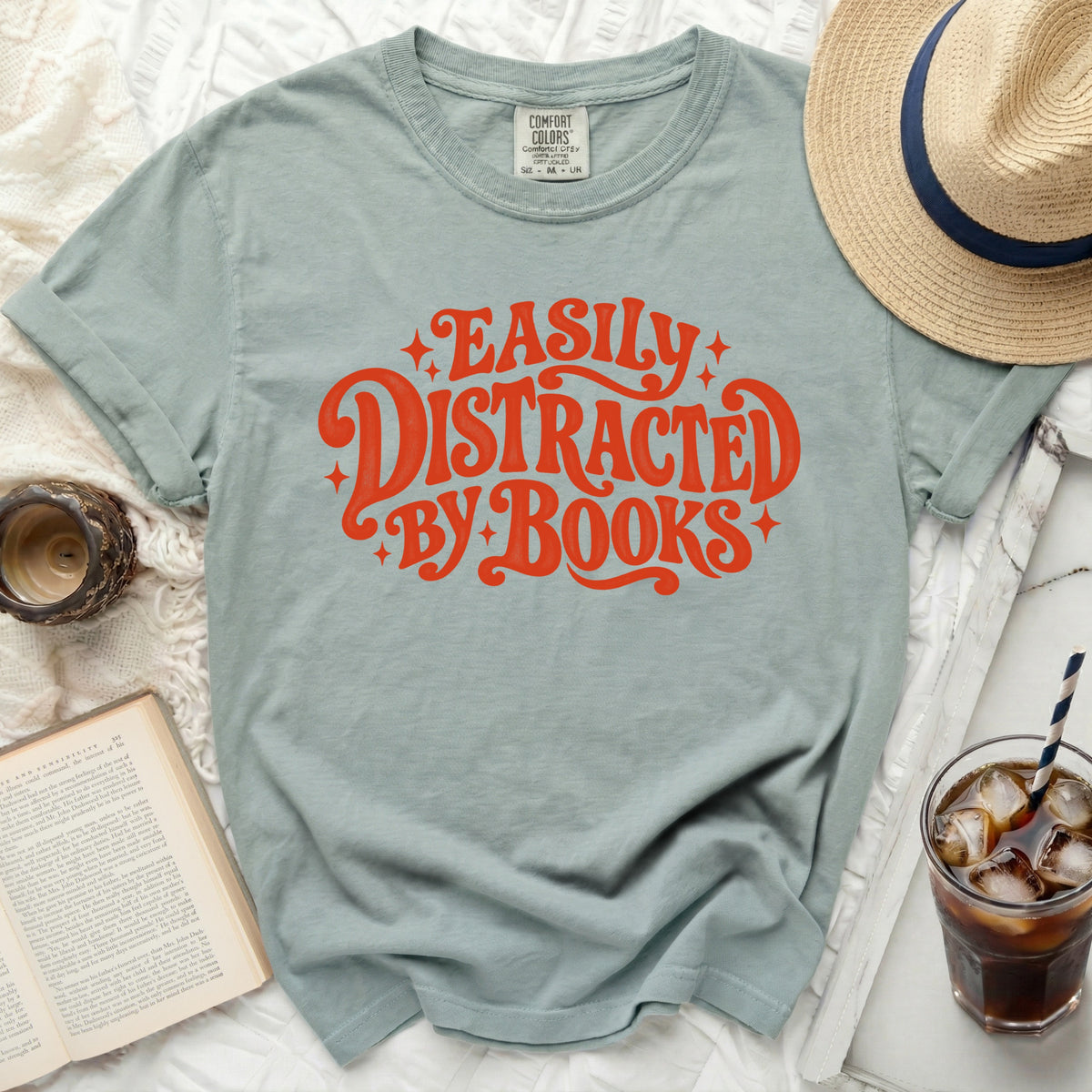 Light blue t-shirt with "Easily Distracted By Books" graphic in orange.