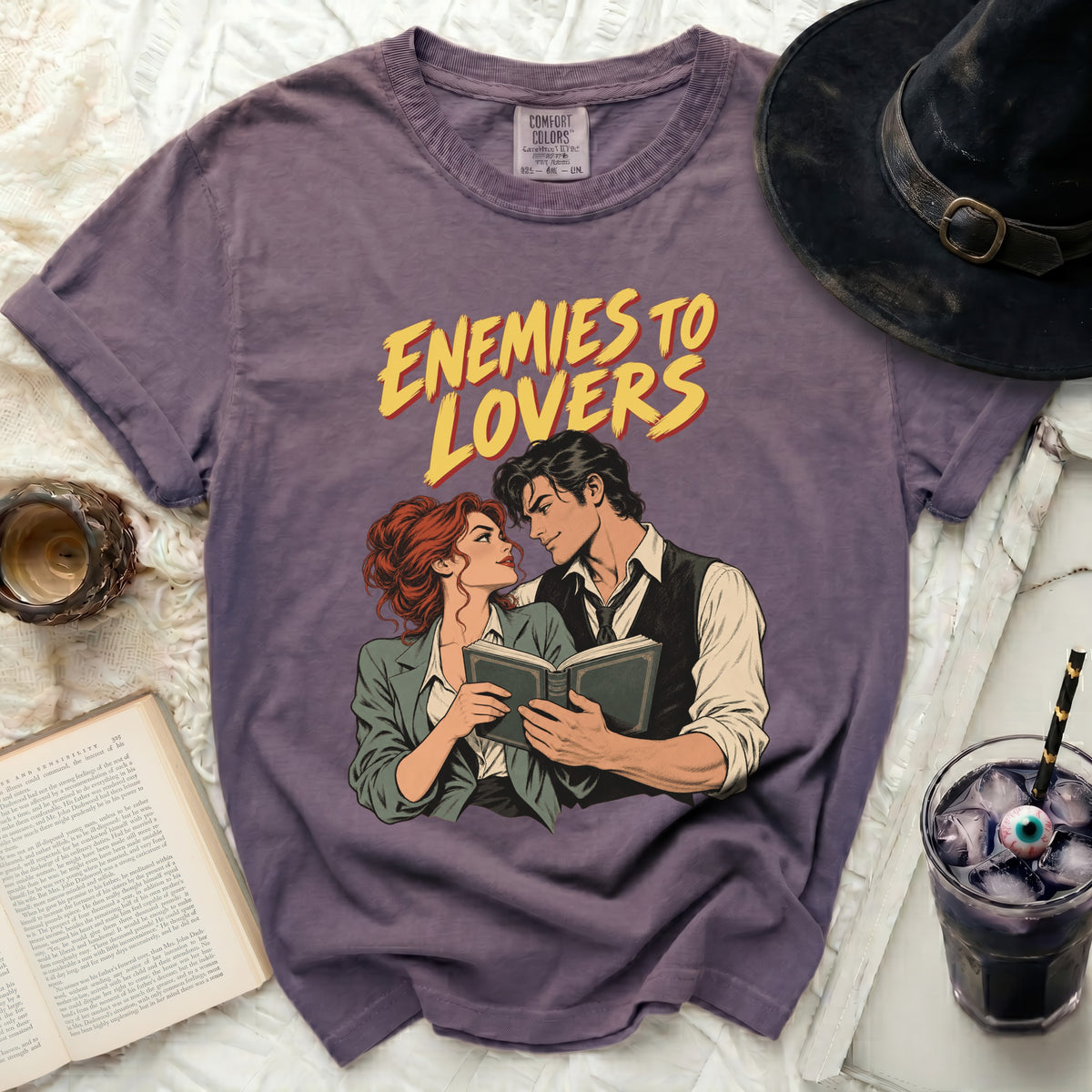 Purple t-shirt with "Enemies to Lovers" comic style print of a couple.
