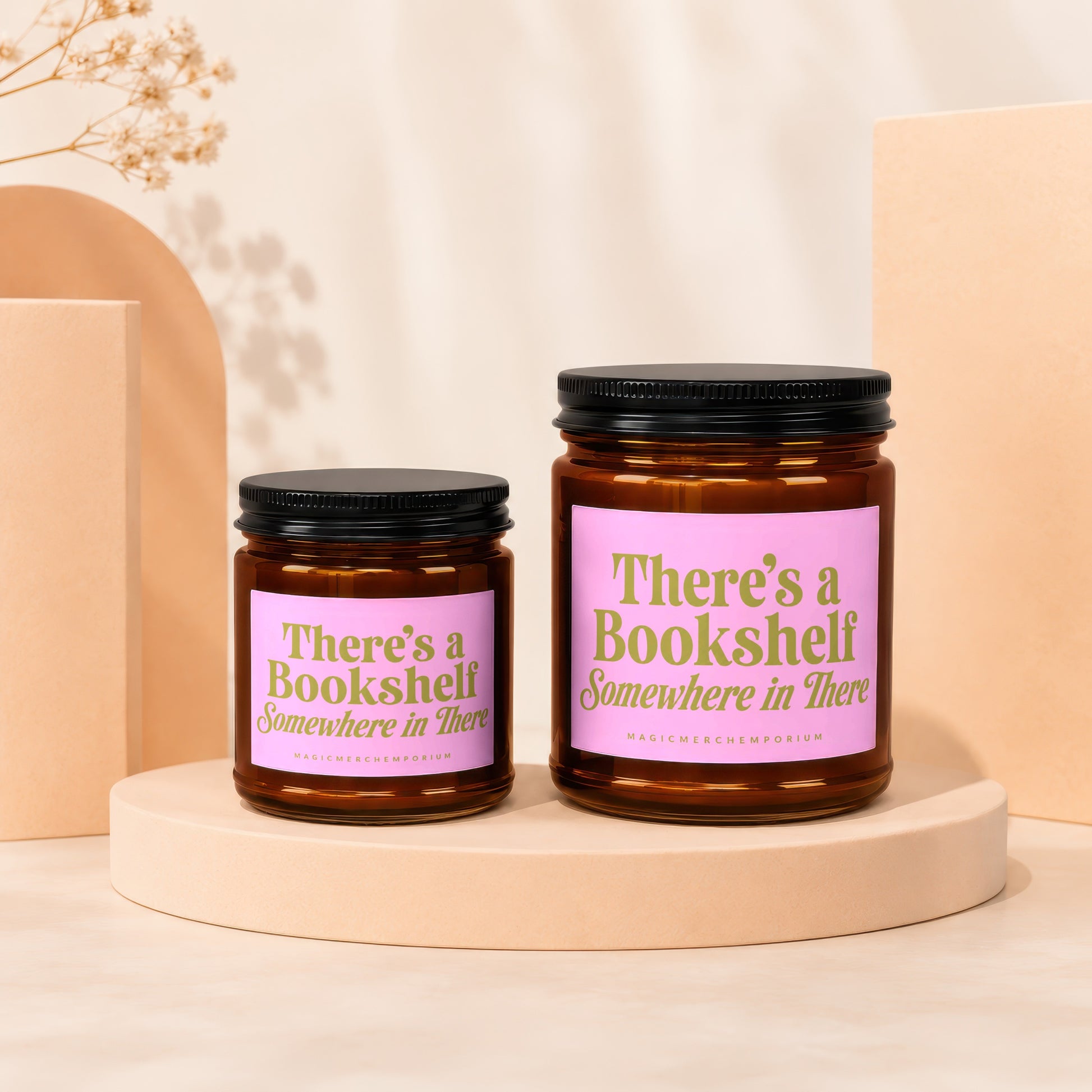 Two amber glass candles with pink labels reading "There's a Bookshelf Somewhere in There".