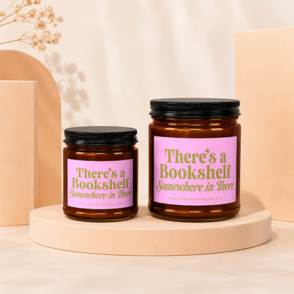 Two amber glass candles with pink labels reading "There's a Bookshelf Somewhere in There".
