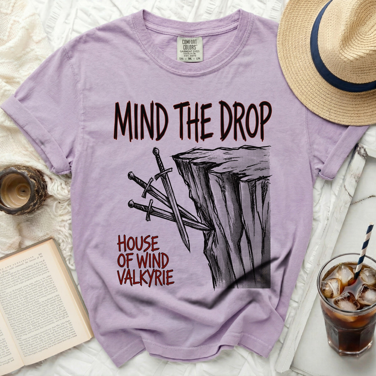 Purple t-shirt with "MIND THE DROP" and swords on a cliff design.