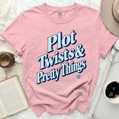 Pink t-shirt with "Plot Twists & Pretty Things" text and heart graphic.