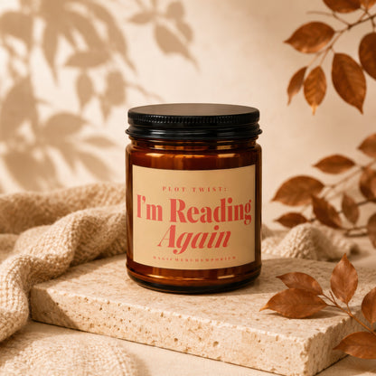 Amber jar candle with black lid, "I'm Reading Again" text, and autumn leaf decor.