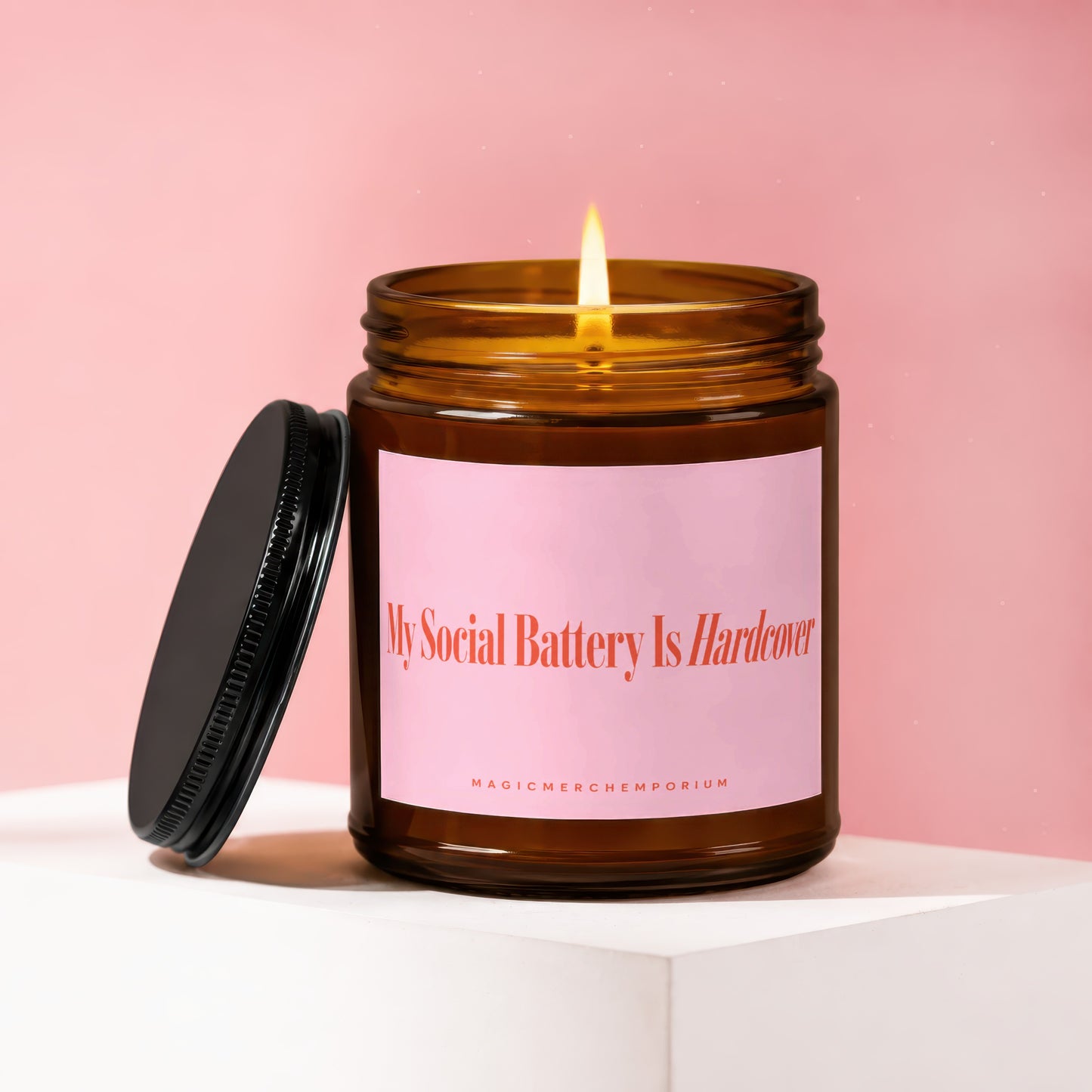 Amber jar candle lit, with lid off, reading "My Social Battery Is Hardcover".
