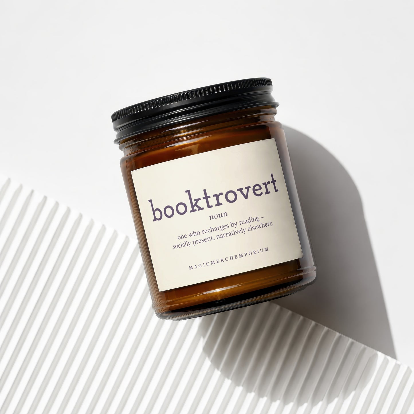 Amber jar candle with black lid, labeled "booktrovert" and "MagicMerchEmporium".