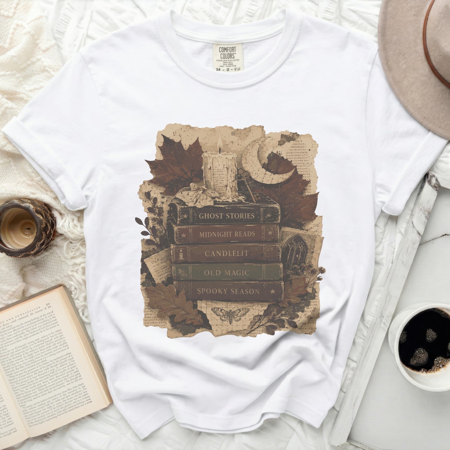 White t-shirt with vintage stacked books print featuring "Ghost Stories" and spooky season imagery.