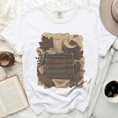 White t-shirt with vintage stacked books print featuring "Ghost Stories" and spooky season imagery.