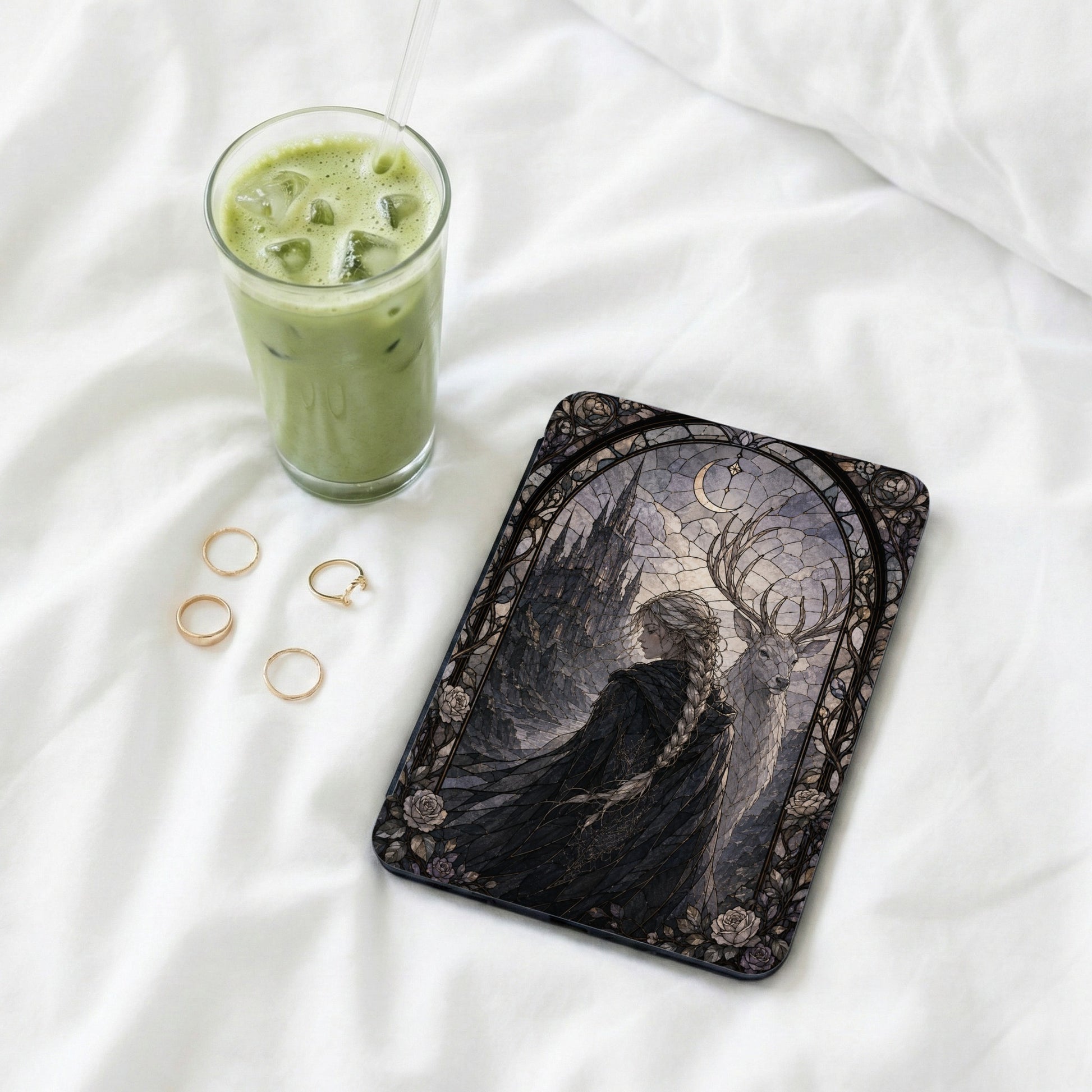 Cover art with stained glass design of a woman and a deer next to a glass of matcha tea.