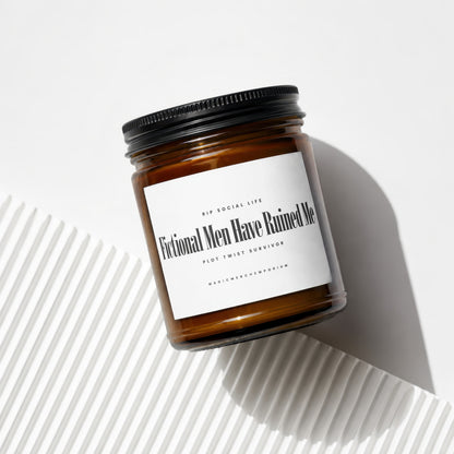 Amber jar candle with black lid reading "Fictional Men Have Ruined Me Plot Twist Survivor"