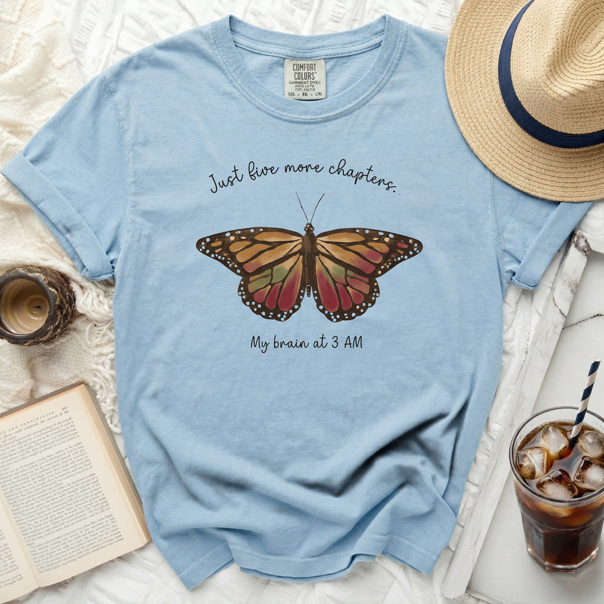 Light blue t-shirt with butterfly graphic and text "Just five more chapters. My brain at 3 AM."