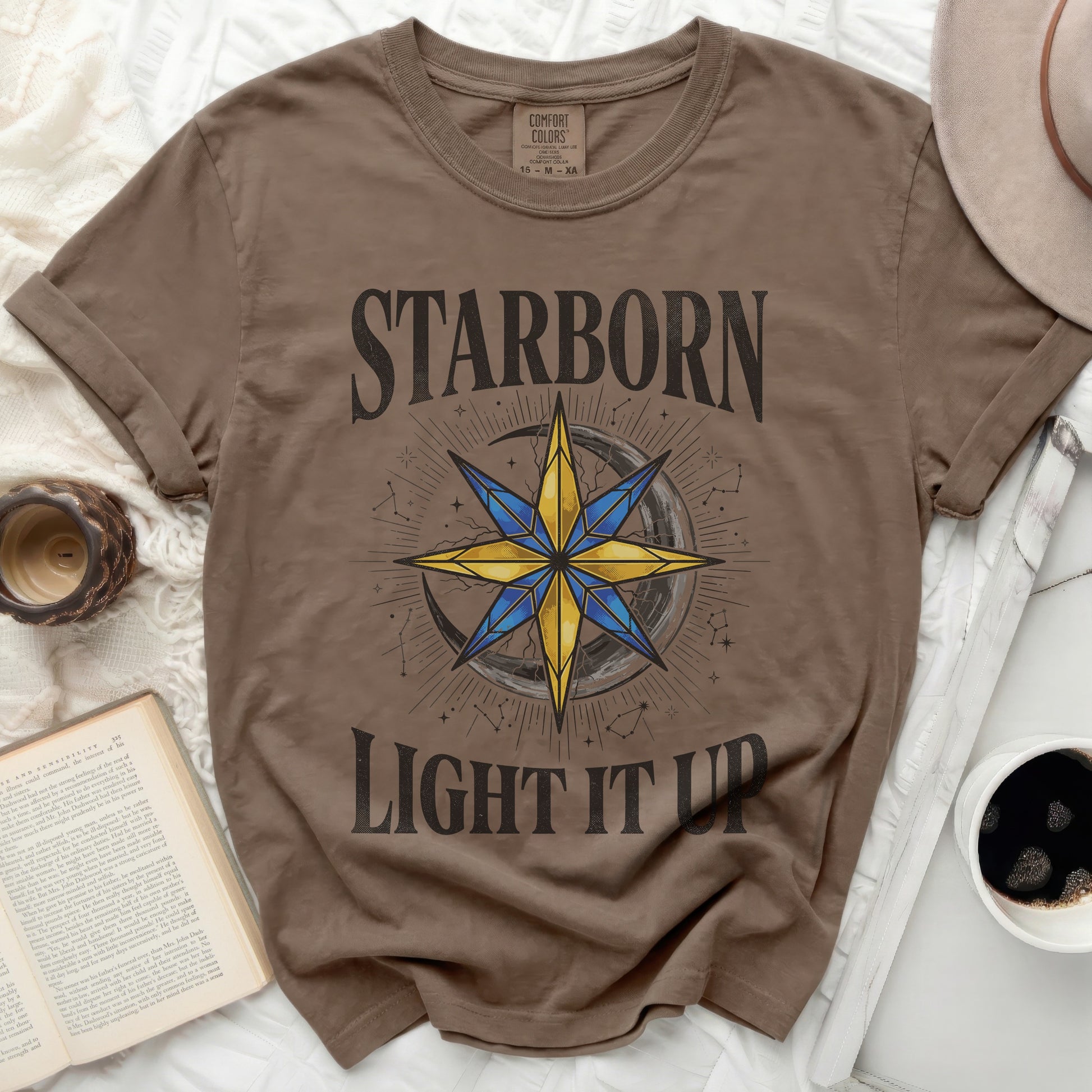 Brown t-shirt with "STARBORN LIGHT IT UP" and a compass rose graphic.