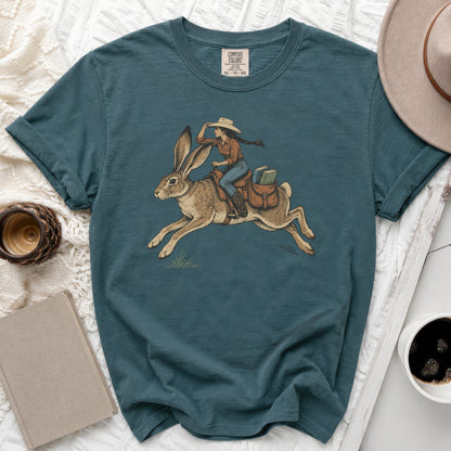 T-shirt with graphic of woman in cowboy hat riding a running rabbit with books.
